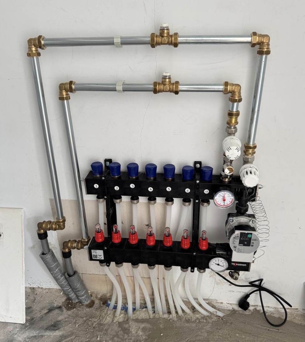 Seven-circuit underfloor heating manifold connected to district heating, with two air vents at the top — Vloerverwarming Arnhem